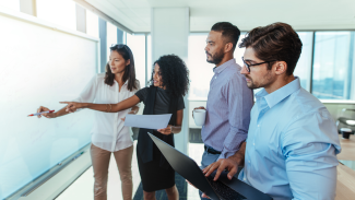 Group of people discussing near a white board